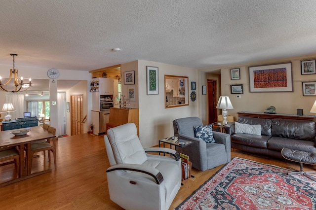 living area featuring light wood-type flooring, a textured ceiling, and an inviting chandelier