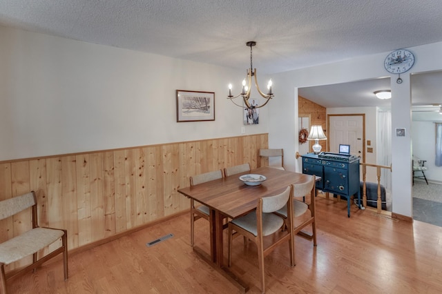 dining space with visible vents, a textured ceiling, and wood finished floors