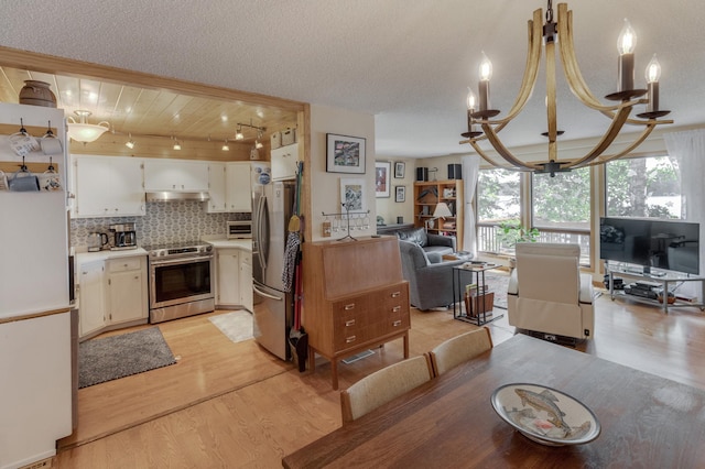 kitchen featuring a notable chandelier, open floor plan, light wood-style floors, appliances with stainless steel finishes, and decorative backsplash