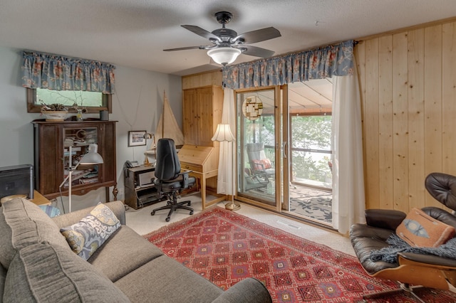 office with carpet flooring, a textured ceiling, a ceiling fan, and wooden walls