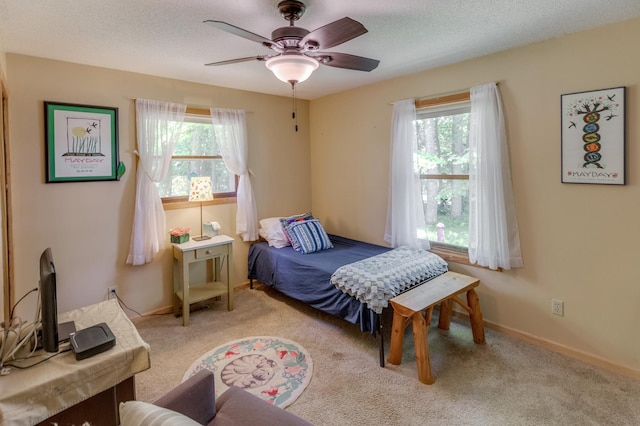 carpeted bedroom featuring ceiling fan, a textured ceiling, and baseboards