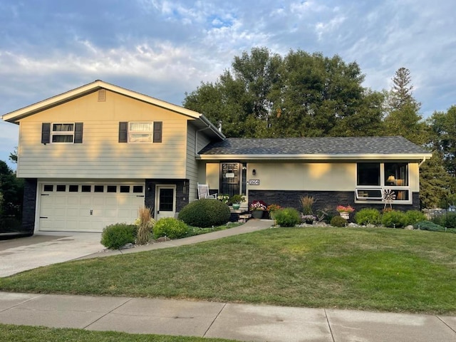 tri-level home with stone siding, an attached garage, concrete driveway, and a front lawn