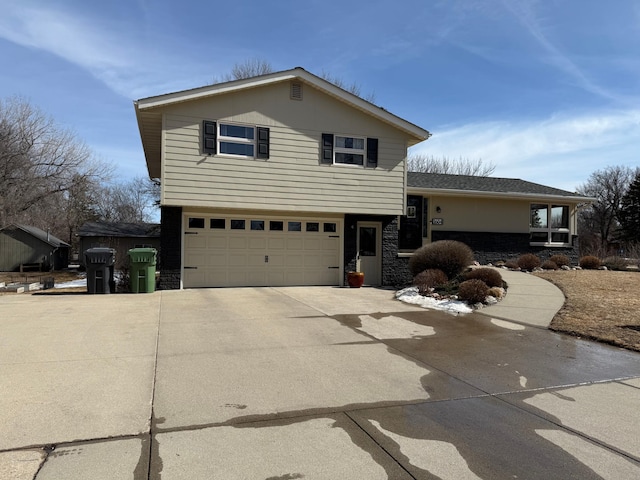 tri-level home with concrete driveway, a garage, and stone siding