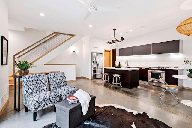 living area with ceiling fan with notable chandelier, recessed lighting, finished concrete flooring, and baseboards