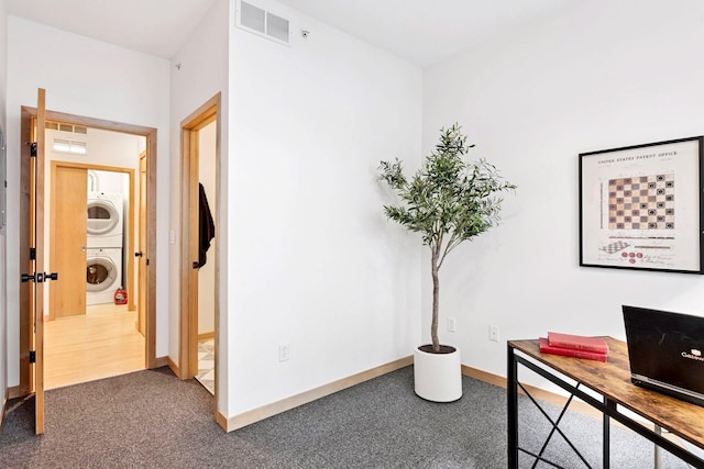 office featuring visible vents, carpet flooring, stacked washer / drying machine, and baseboards