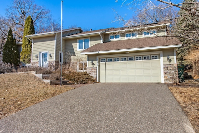 view of front of property featuring stone siding, driveway, and an attached garage