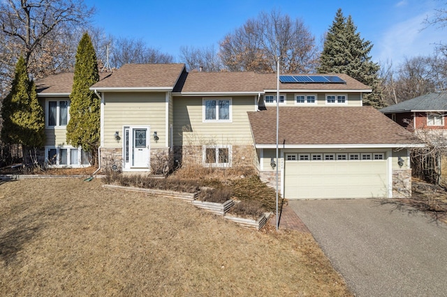 view of front of property with aphalt driveway, an attached garage, solar panels, a shingled roof, and stone siding