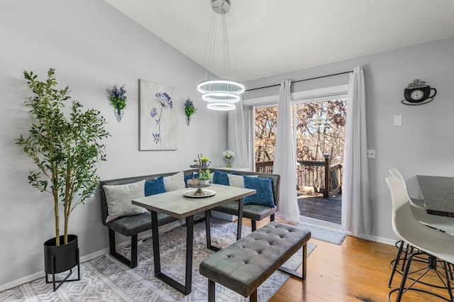 dining space with light wood-type flooring, baseboards, breakfast area, and vaulted ceiling