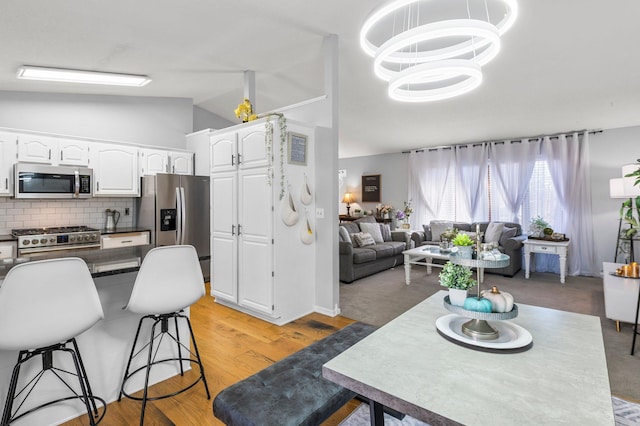 kitchen featuring dark countertops, vaulted ceiling, white cabinets, and stainless steel appliances