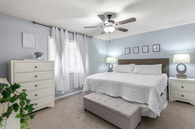 bedroom with light carpet, a ceiling fan, and a textured ceiling