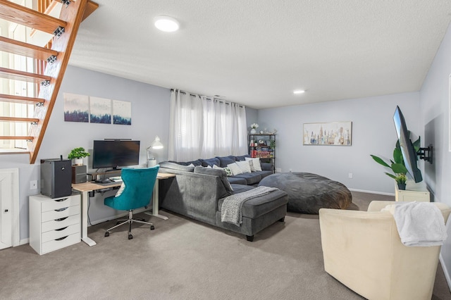 carpeted living area with a textured ceiling and stairs