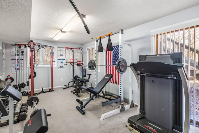 exercise area featuring carpet flooring, a textured ceiling, and baseboards