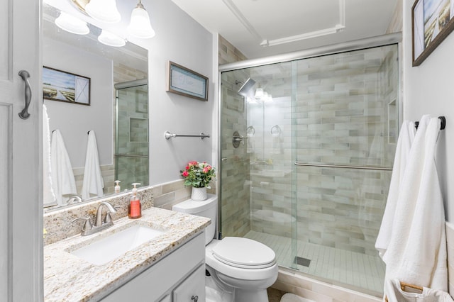 bathroom featuring toilet, a shower stall, and vanity