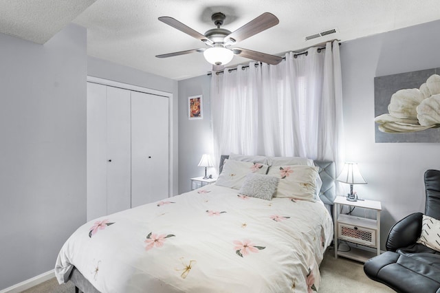 bedroom with a closet, visible vents, a ceiling fan, carpet flooring, and a textured ceiling