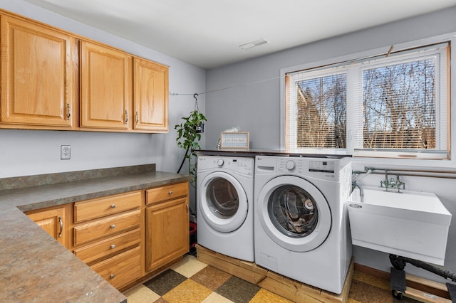 laundry area featuring a sink, visible vents, cabinet space, light floors, and washer and clothes dryer