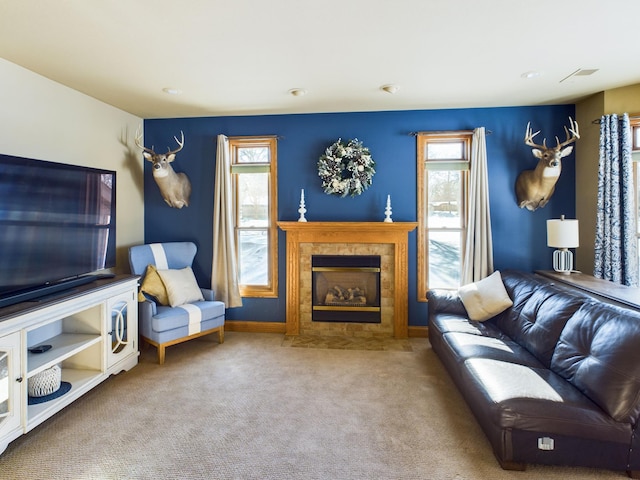 living area featuring a tiled fireplace, carpet flooring, and baseboards