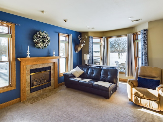 carpeted living room featuring baseboards, a fireplace, and visible vents