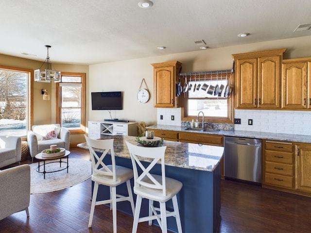 kitchen featuring a center island, pendant lighting, open floor plan, a sink, and dishwasher