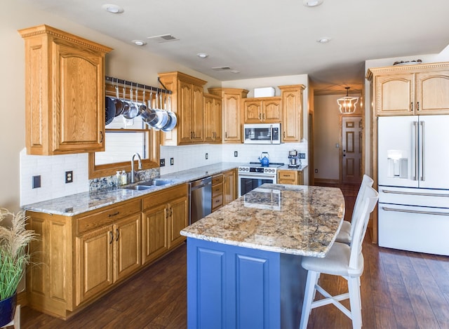 kitchen featuring visible vents, light stone counters, a center island, stainless steel appliances, and a sink