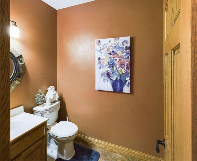 half bathroom featuring baseboards, vanity, and toilet