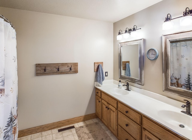 bathroom with visible vents, a sink, baseboards, and double vanity