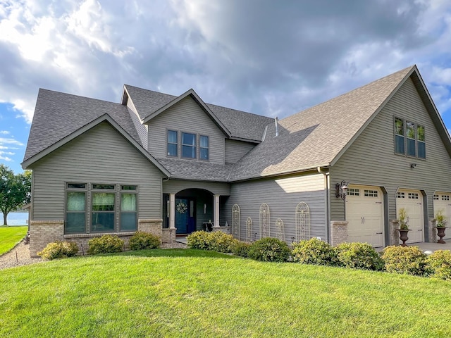 view of front facade with a shingled roof, a front yard, brick siding, and a garage