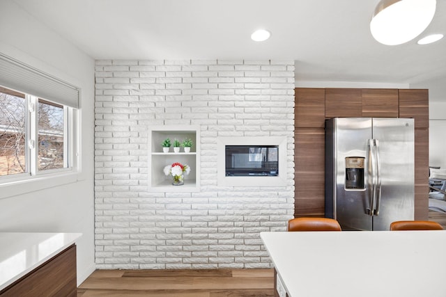 kitchen featuring modern cabinets, stainless steel fridge, light wood-style floors, brown cabinetry, and light countertops