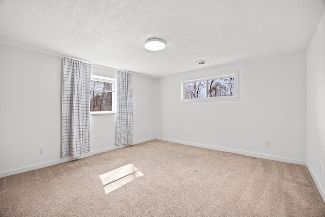 carpeted spare room featuring visible vents, baseboards, and a textured ceiling