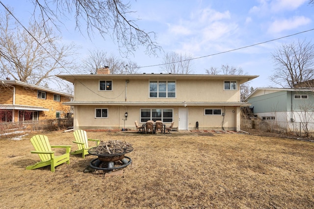 back of property with a patio area, stucco siding, a chimney, and an outdoor fire pit