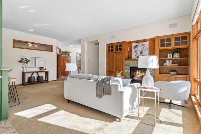 living room with visible vents, light colored carpet, and a glass covered fireplace