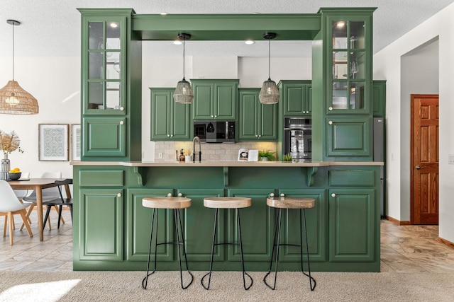 kitchen with glass insert cabinets, decorative light fixtures, light countertops, green cabinets, and black oven