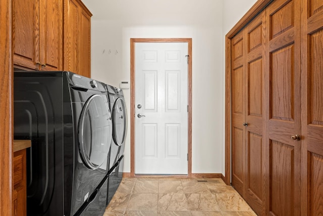 washroom with washing machine and dryer, cabinet space, and baseboards