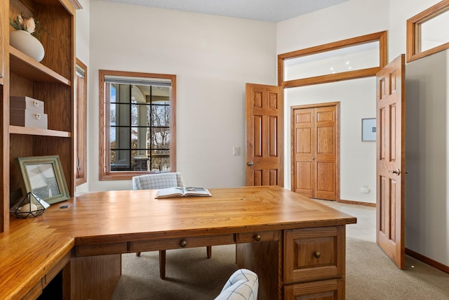 unfurnished office featuring baseboards and light colored carpet