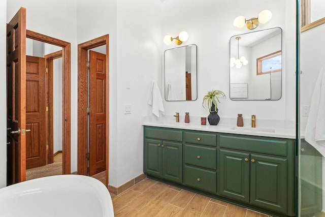 bathroom with wood finished floors, a sink, baseboards, and double vanity