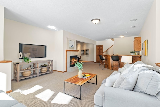 living area with light carpet, baseboards, and a tile fireplace