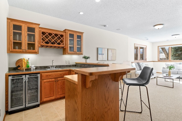 bar featuring wine cooler, light tile patterned floors, a sink, a textured ceiling, and wet bar