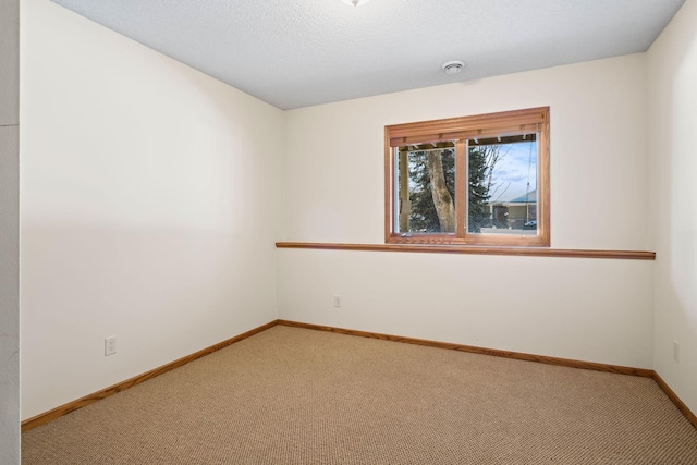 carpeted spare room with a textured ceiling and baseboards