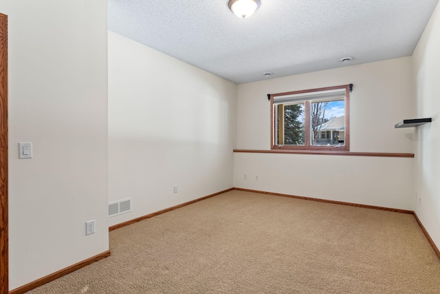 carpeted empty room featuring a textured ceiling, visible vents, and baseboards