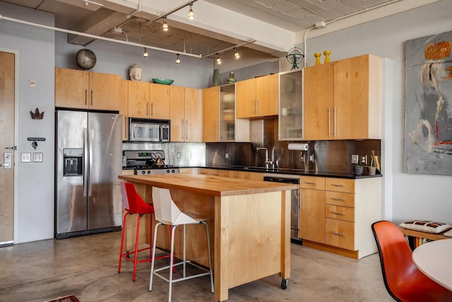 225 9th St E Unit 504, Saint Paul, MN 55101 - kitchen with stainless steel appliances, butcher block counters, concrete flooring, decorative backsplash, and a kitchen breakfast bar