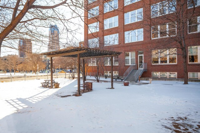 225 9th St E Unit 504, Saint Paul, MN 55101 - snow covered property featuring brick siding, a pergola, and a chimney