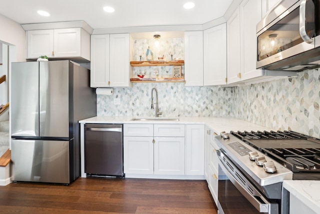 kitchen featuring stainless steel appliances, white cabinetry, a sink, and backsplash