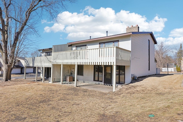 back of house with a chimney, a patio area, and a wooden deck