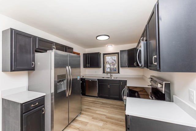 kitchen with light wood-style floors, stainless steel appliances, a sink, and light countertops