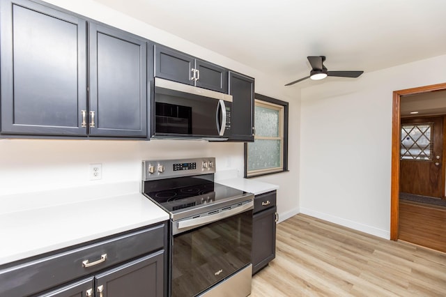 kitchen with stainless steel appliances, light wood finished floors, light countertops, and baseboards