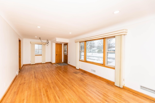 unfurnished room with light wood-style floors, visible vents, and baseboards