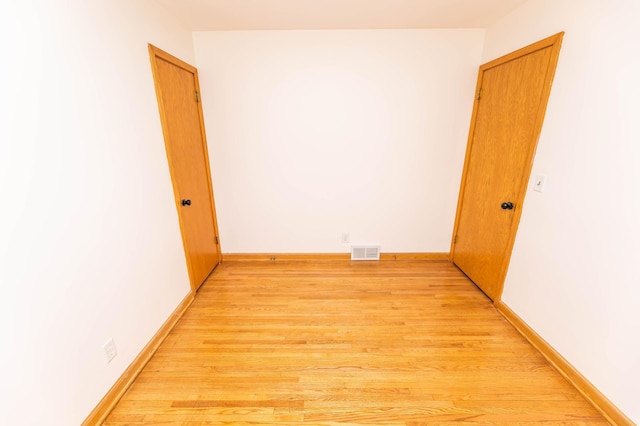 empty room featuring light wood-style floors, baseboards, and visible vents