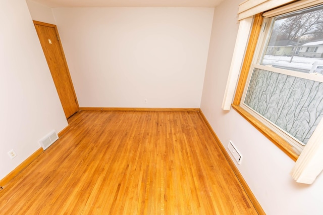 spare room featuring light wood-style floors, baseboards, and visible vents