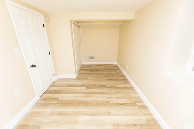 corridor featuring baseboards, visible vents, and light wood-style floors