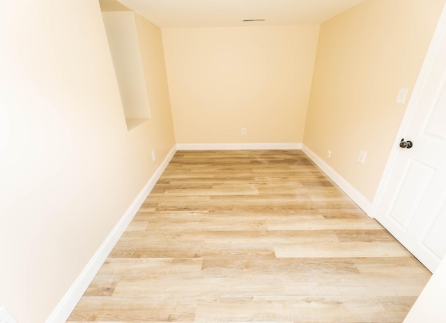 unfurnished room with light wood-style floors, visible vents, and baseboards