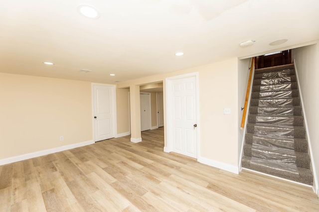 finished below grade area with stairway, recessed lighting, light wood-style flooring, and baseboards